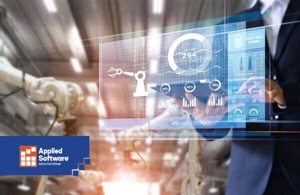 穿着蓝色西装的人在半透明的制造仪表盘后面拿着打开的笔记本电脑，条形图背景模糊了工厂里的机器人设备