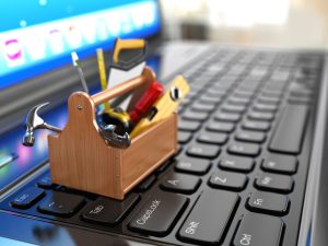 小型木工工具箱工具伸出坐在黑色的电脑键盘,电脑显示器显示的蓝色和白色屏幕背景