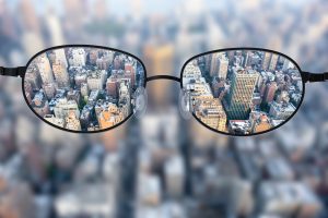 从上面看模糊的城市通过眼镜,清晰可见的市政大楼通过两个镜片